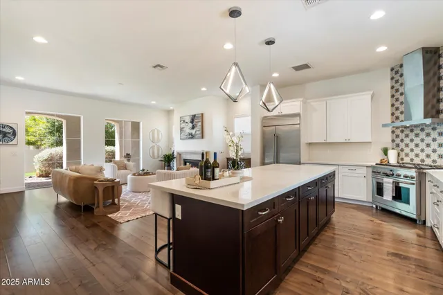 a open kitchen with stainless steel appliances granite countertop a sink dishwasher a stove a dining table and chairs with wooden floor