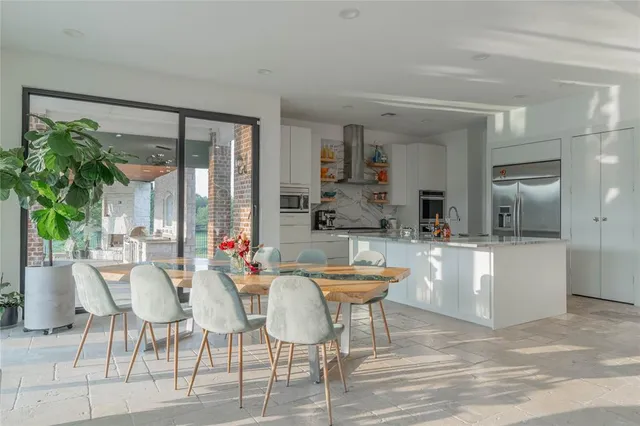 a dining hall with stainless steel appliances kitchen island granite countertop a table and chairs in it