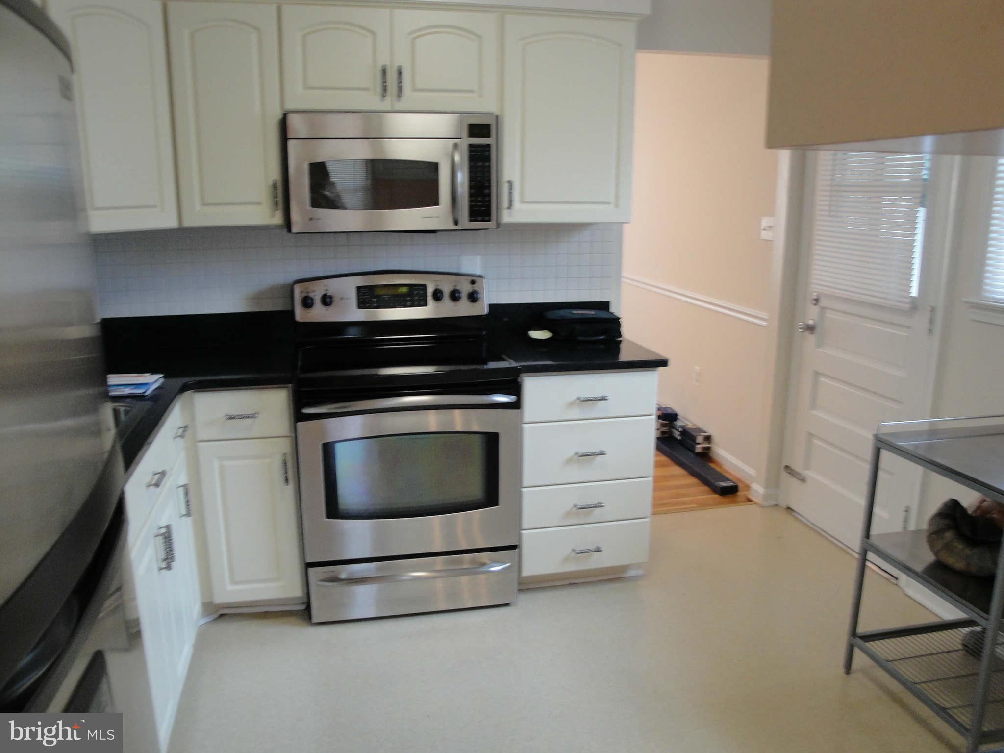 13212 Tamarack Road Silver Spring, MD 20904 - Photo 3 of 28 a kitchen with stainless steel appliances a stove a microwave and cabinets