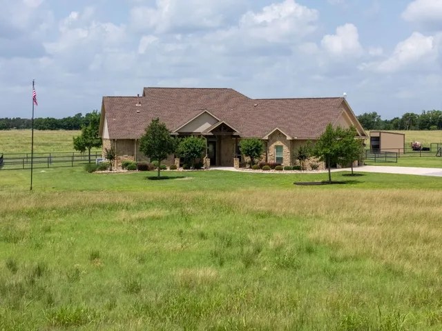 a view of house with a big yard and potted plants