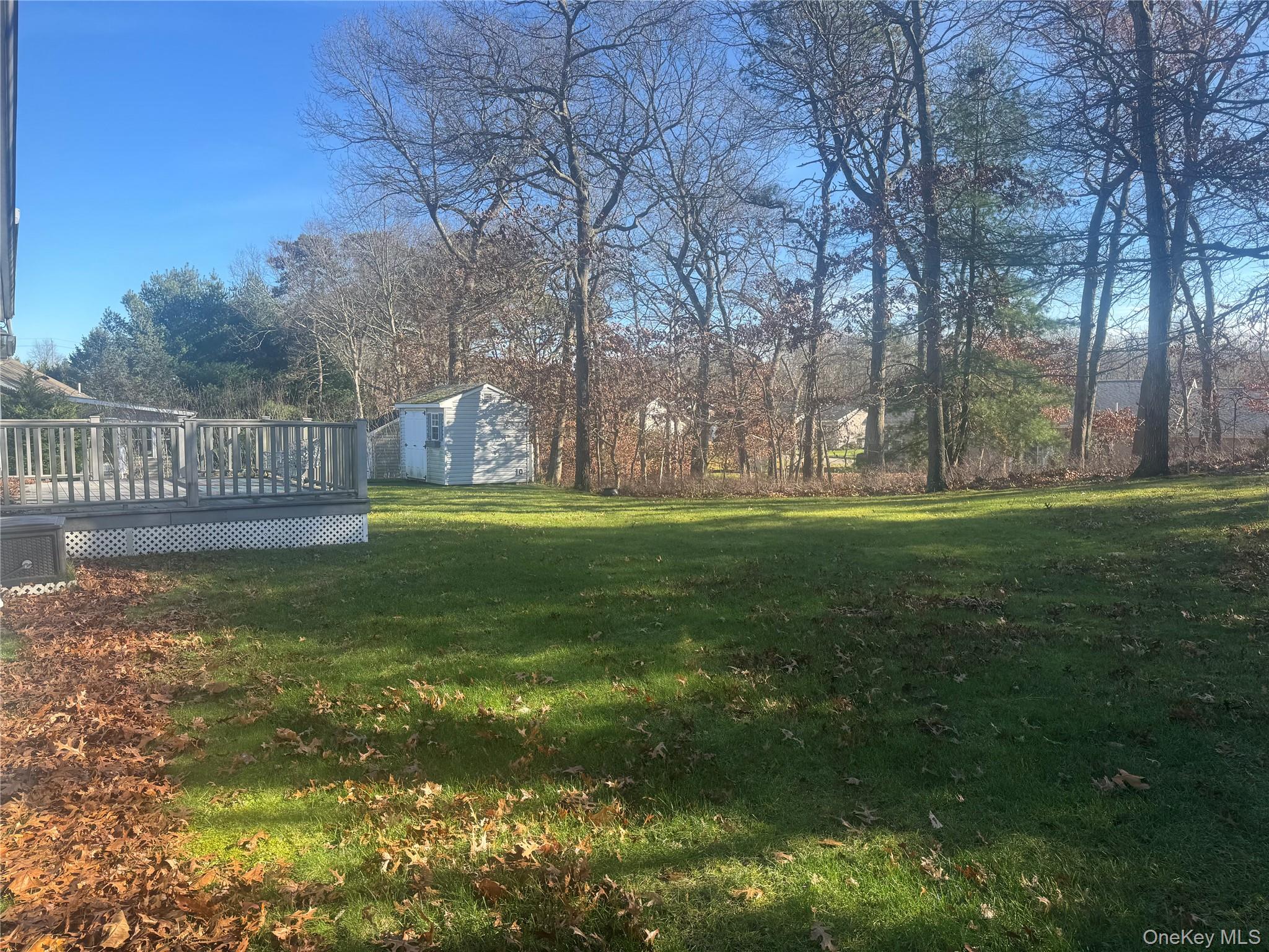 1407 Middle Road, Unit 275 Calverton, NY 11933 - Photo 21 of 24 View of green lawn with a wooden deck and an outdoor structure