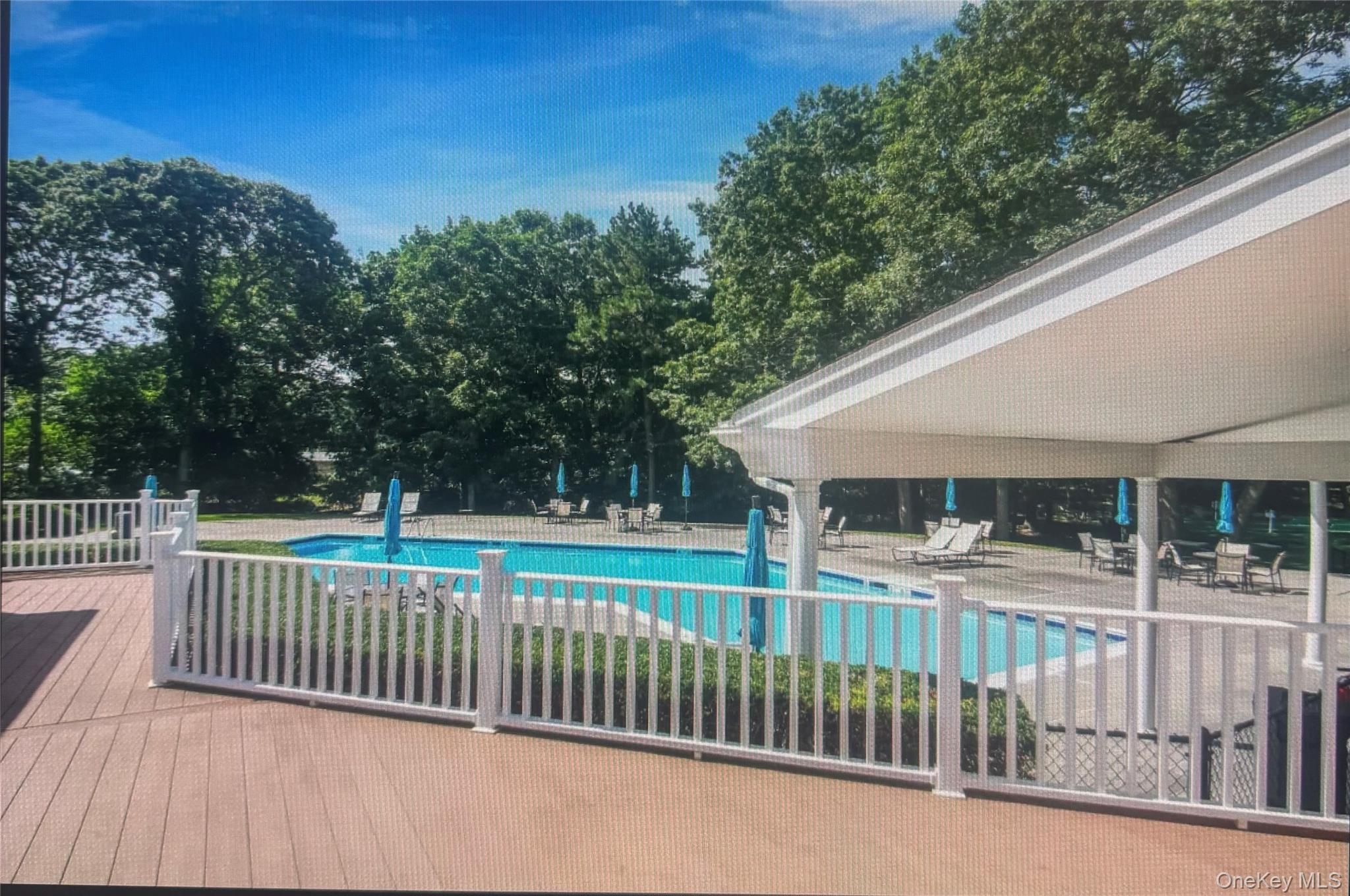 1407 Middle Road, Unit 275 Calverton, NY 11933 - Photo 23 of 24 Community pool featuring a patio and view of wooded area