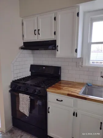 a kitchen with granite countertop white cabinets and black stove top oven