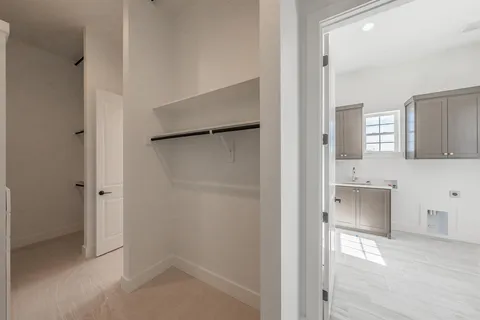 an empty room with chandelier fan and windows