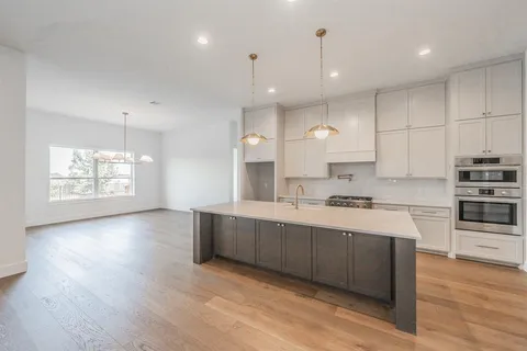 a large kitchen with stainless steel appliances kitchen island granite countertop a stove a sink and a wooden floors