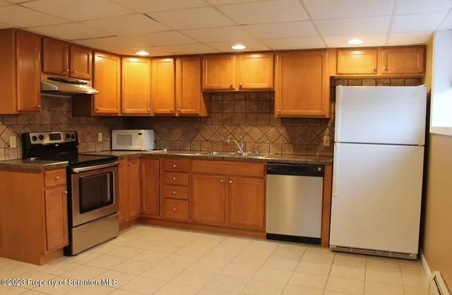 a kitchen with stainless steel appliances granite countertop a refrigerator a sink and a stove