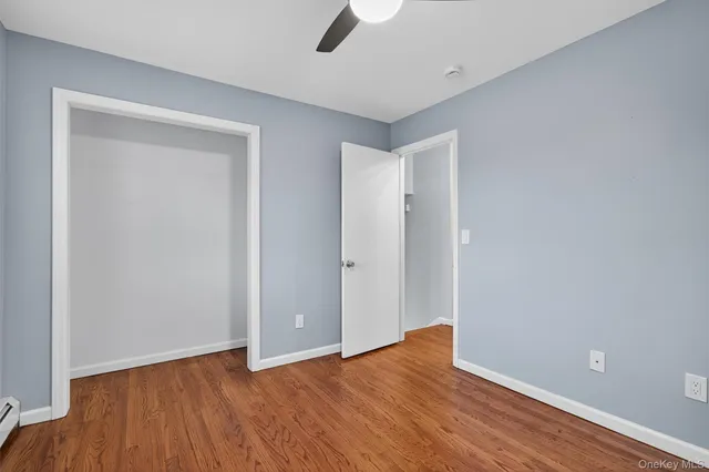 a view of an empty room with wooden floor and a ceiling fan