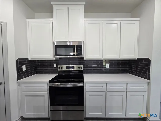 a kitchen with white cabinets and black appliances