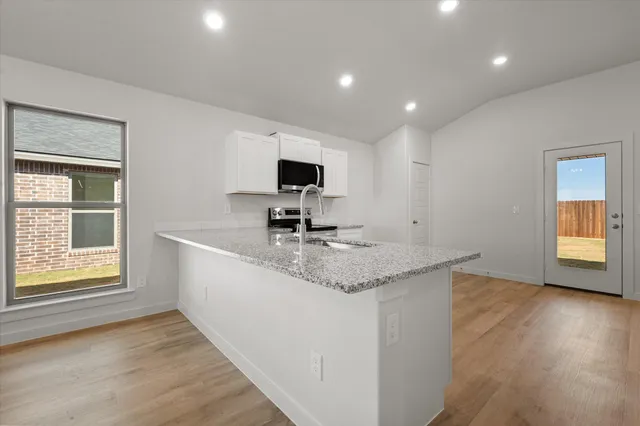 a kitchen with stainless steel appliances granite countertop a stove a sink and a microwave