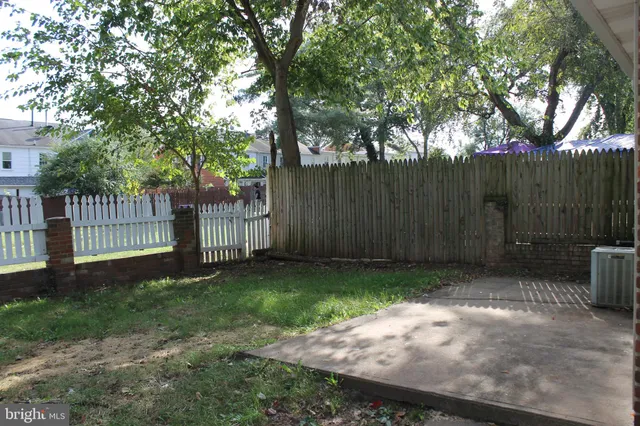 a view of a backyard with wooden fence and large trees