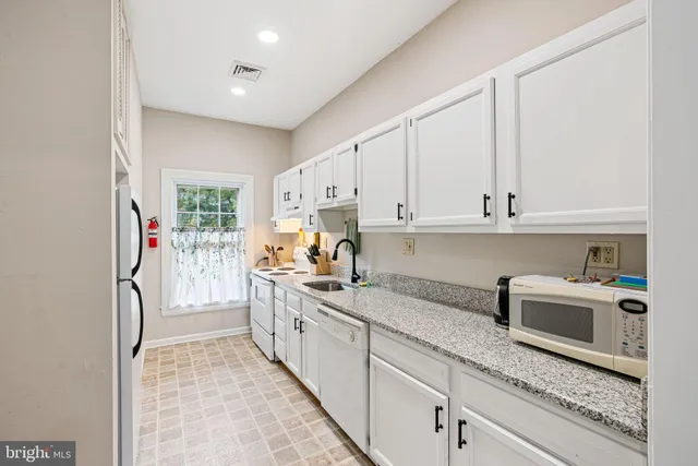 a kitchen with white cabinets and sink