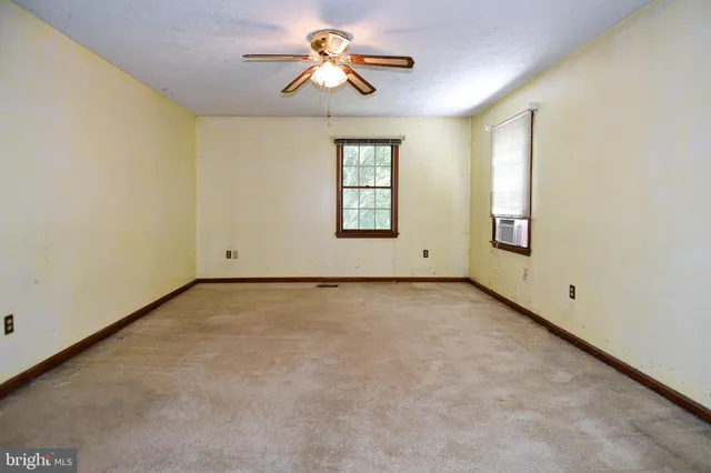 an empty room with windows and chandelier fan