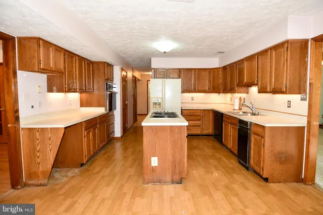 a large kitchen with a stove a sink dishwasher and a refrigerator with wooden floor