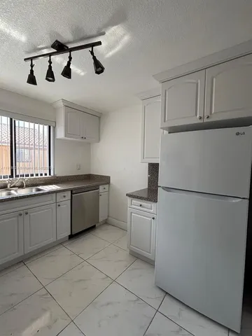 a kitchen with stainless steel appliances granite countertop a refrigerator a sink a stove a microwave and cabinets