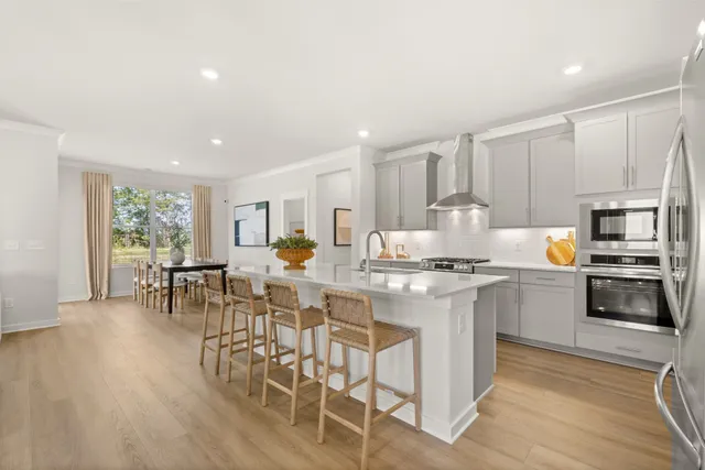 a kitchen with stainless steel appliances kitchen island granite countertop a stove a sink a refrigerator and white cabinets with wooden floor