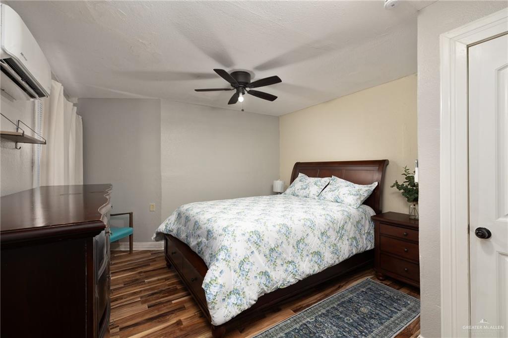 411 East 4th Street Rio Grande City, TX 78582 - Photo 8 of 12 Bedroom featuring wood-finish flooring, a ceiling fan, and a wall-mounted mini-split AC unit