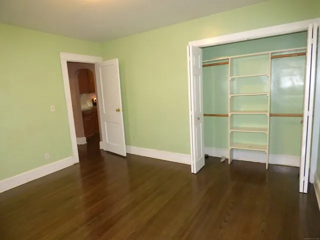 a view of empty room with wooden floor and window