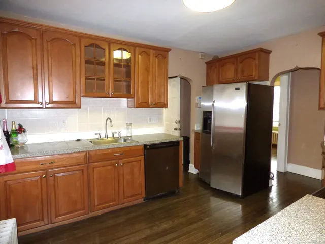 a kitchen with stainless steel appliances granite countertop a refrigerator a sink and dishwasher with wooden floor