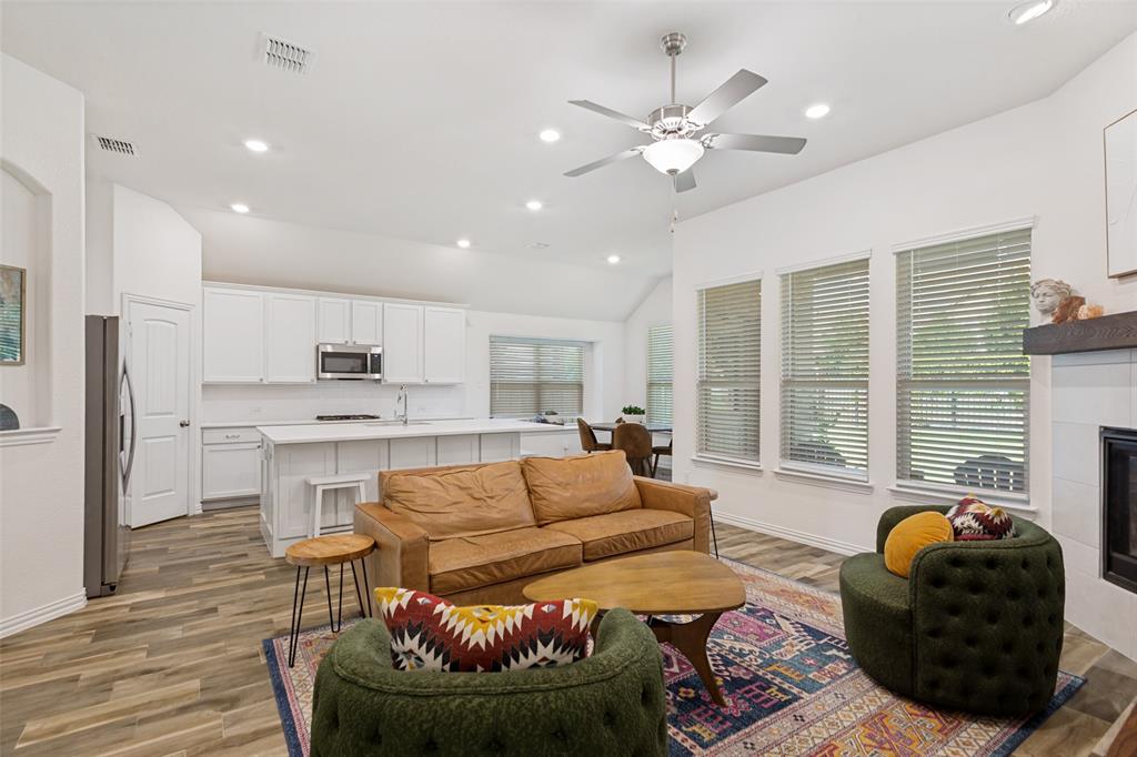 5556 Vaquero Road Fort Worth, TX 76126 - Photo 9 of 25 Open-concept living space featuring wood-finish flooring, a contemporary ceiling fan, recessed lighting, and a white tile fireplace with a dark wood mantel