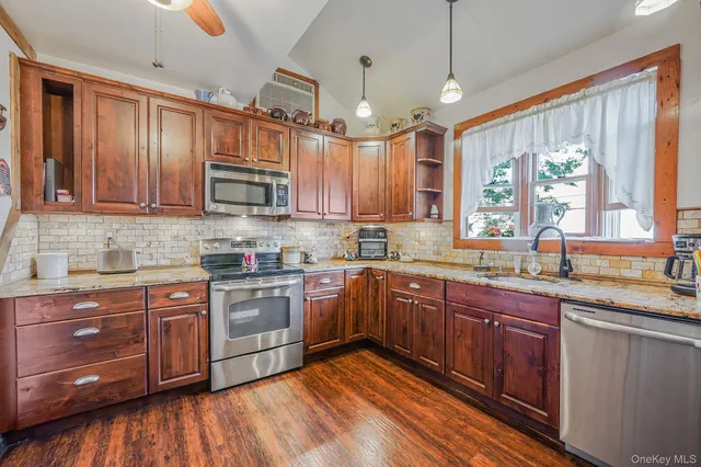 a kitchen with stainless steel appliances granite countertop wooden cabinets a sink and dishwasher a stove with wooden floor