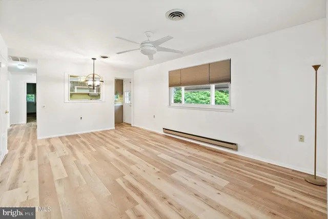 an empty room with wooden floor ceiling fan and windows