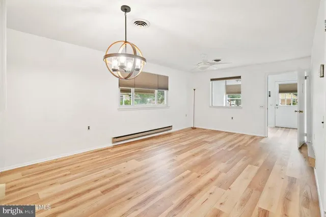 a view of empty room with wooden floor and fan