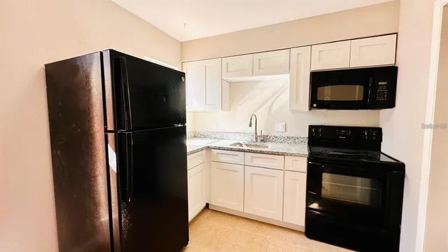 a kitchen with a refrigerator and white cabinets