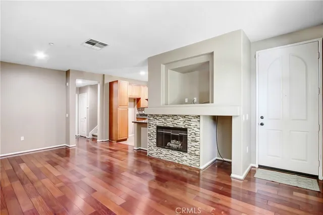 a view of an empty room with wooden floor and a fireplace