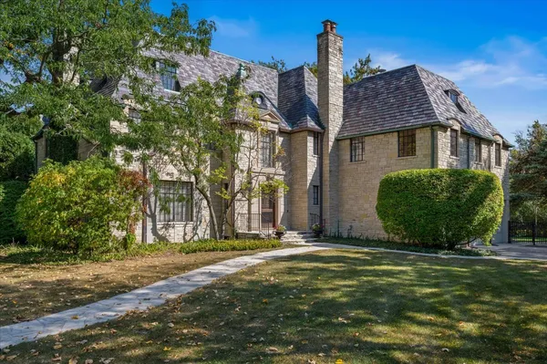 a view of a big house with a big yard and large trees