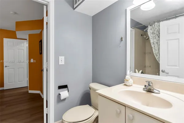 a bathroom with a granite countertop sink toilet and mirror