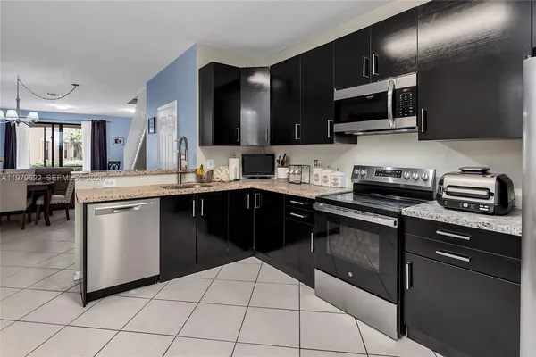 a kitchen with stainless steel appliances kitchen island granite countertop a sink counter space cabinets and a couch