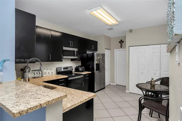 a kitchen with stainless steel appliances kitchen island granite countertop a sink refrigerator and stove