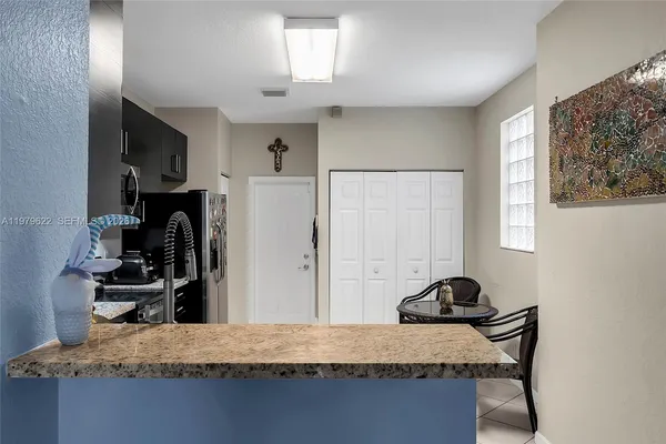 a living room with kitchen island granite countertop furniture a flat screen tv and a refrigerator