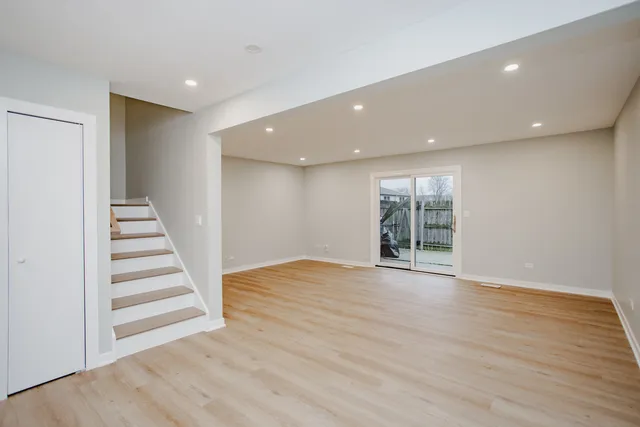 a view of an empty room with wooden floor and stairs