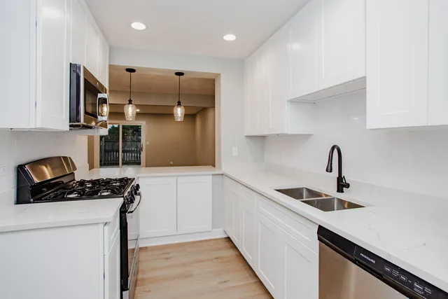 a kitchen with stainless steel appliances a sink dishwasher a stove a refrigerator and wooden floor