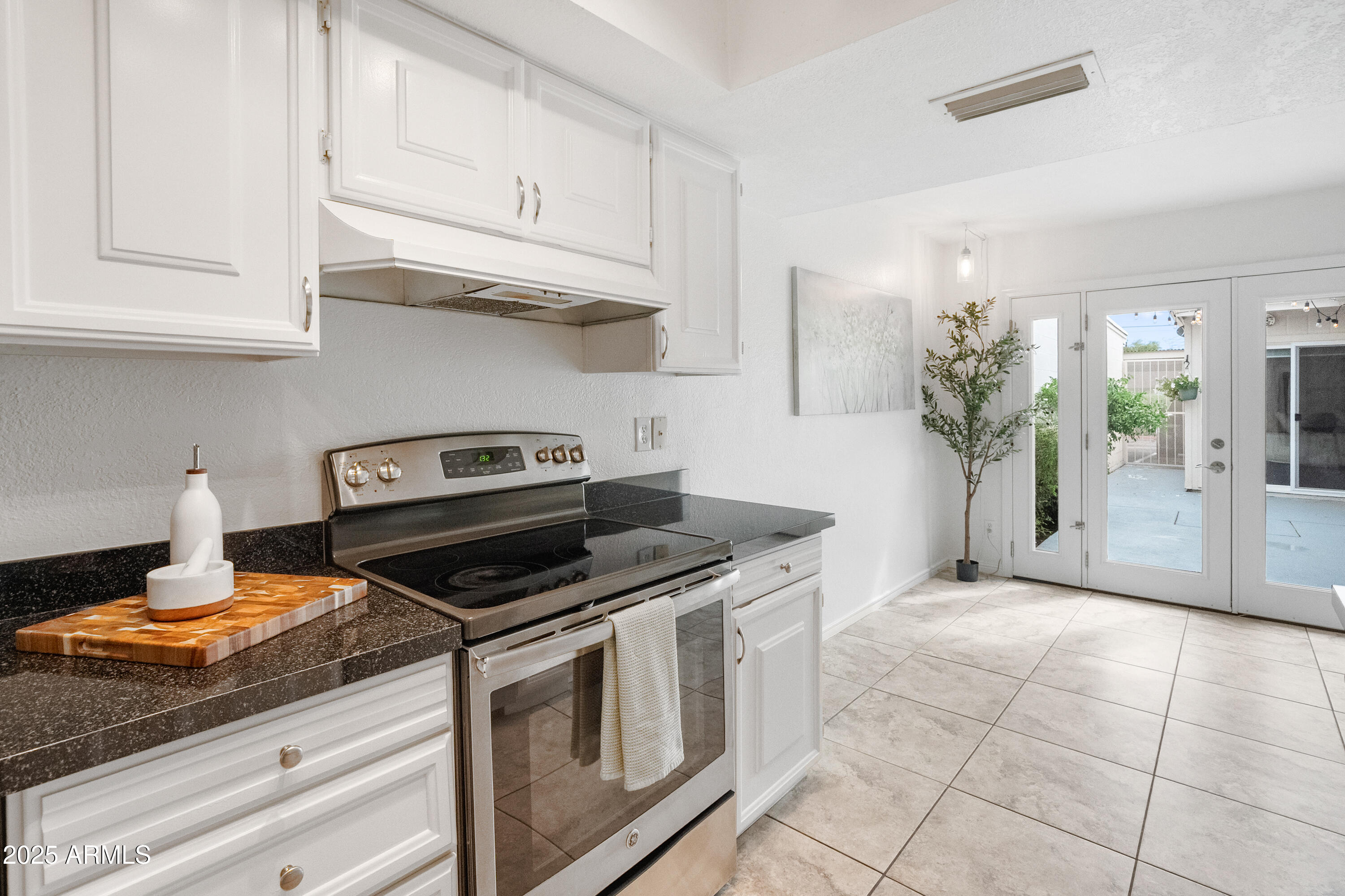3928 North Granite Reef Road Scottsdale, AZ 85251 - Photo 15 of 30 a kitchen with stainless steel appliances granite countertop a stove a sink and a white cabinets