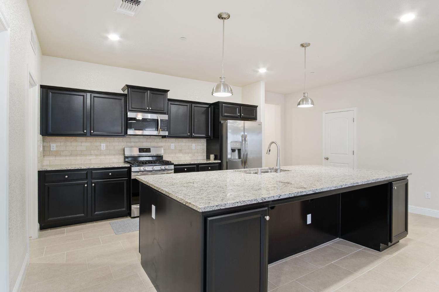 3790 Bonifacio Way Merced, CA 95340 - Photo 11 of 21 a kitchen with a sink a stove a refrigerator and a microwave