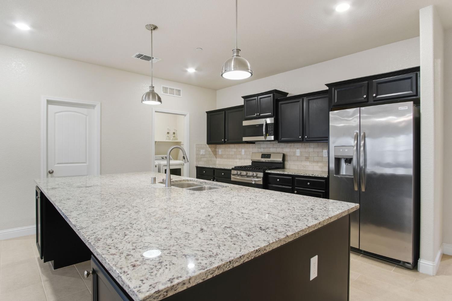 3790 Bonifacio Way Merced, CA 95340 - Photo 10 of 21 a kitchen with stainless steel appliances granite countertop a sink refrigerator and microwave