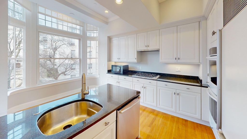 22 Beacon Street, Unit 3 Boston, MA 02108 - Photo 16 of 28 a kitchen with kitchen island a large window cabinets and stainless steel appliances
