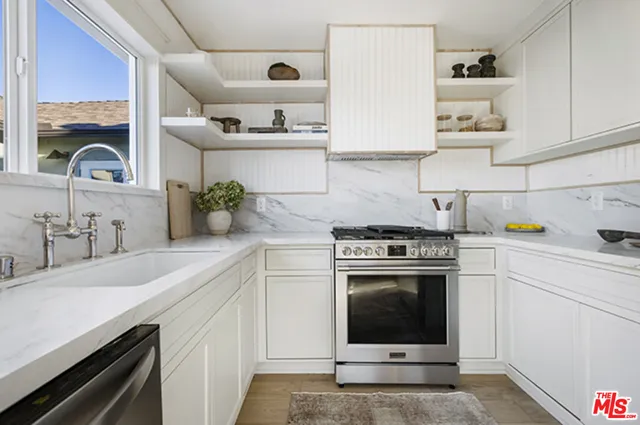a kitchen with stainless steel appliances granite countertop a sink a stove and a wooden floors