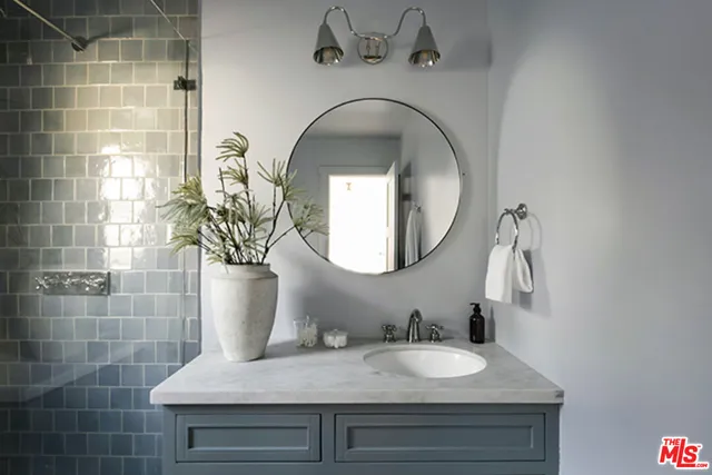 a bathroom with a granite countertop sink a mirror and a shower