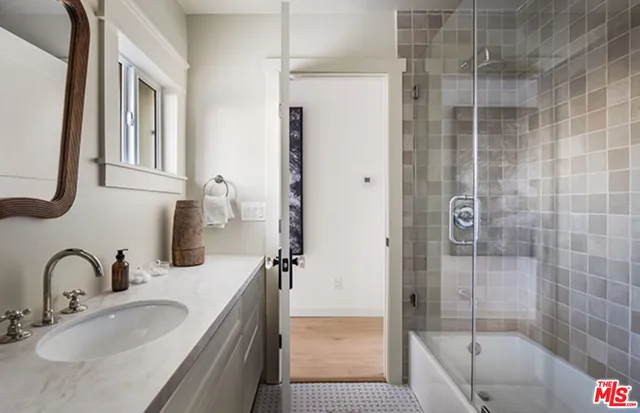 a bathroom with a granite countertop sink a mirror and shower