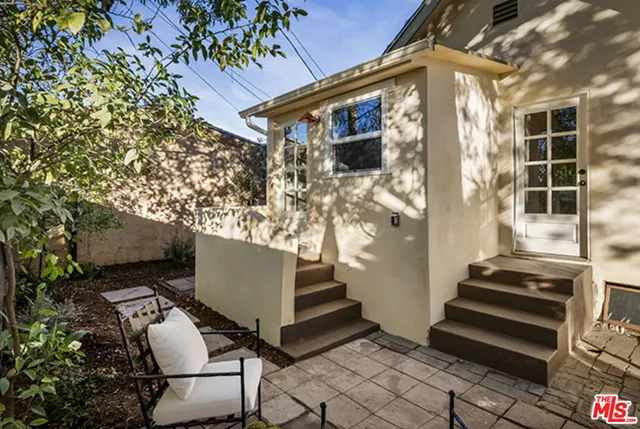 a view of backyard with table and chairs and potted plants