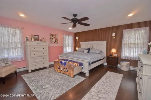 a spacious bedroom with a bed a dresser and a chandelier