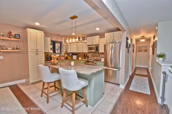 a kitchen with stainless steel appliances a refrigerator a stove a sink dishwasher and a dining table with wooden floor