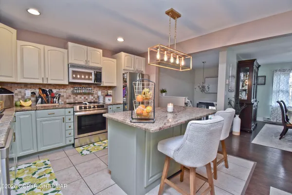 a open kitchen with stainless steel appliances granite countertop a stove top oven a dining table and chairs with wooden floor