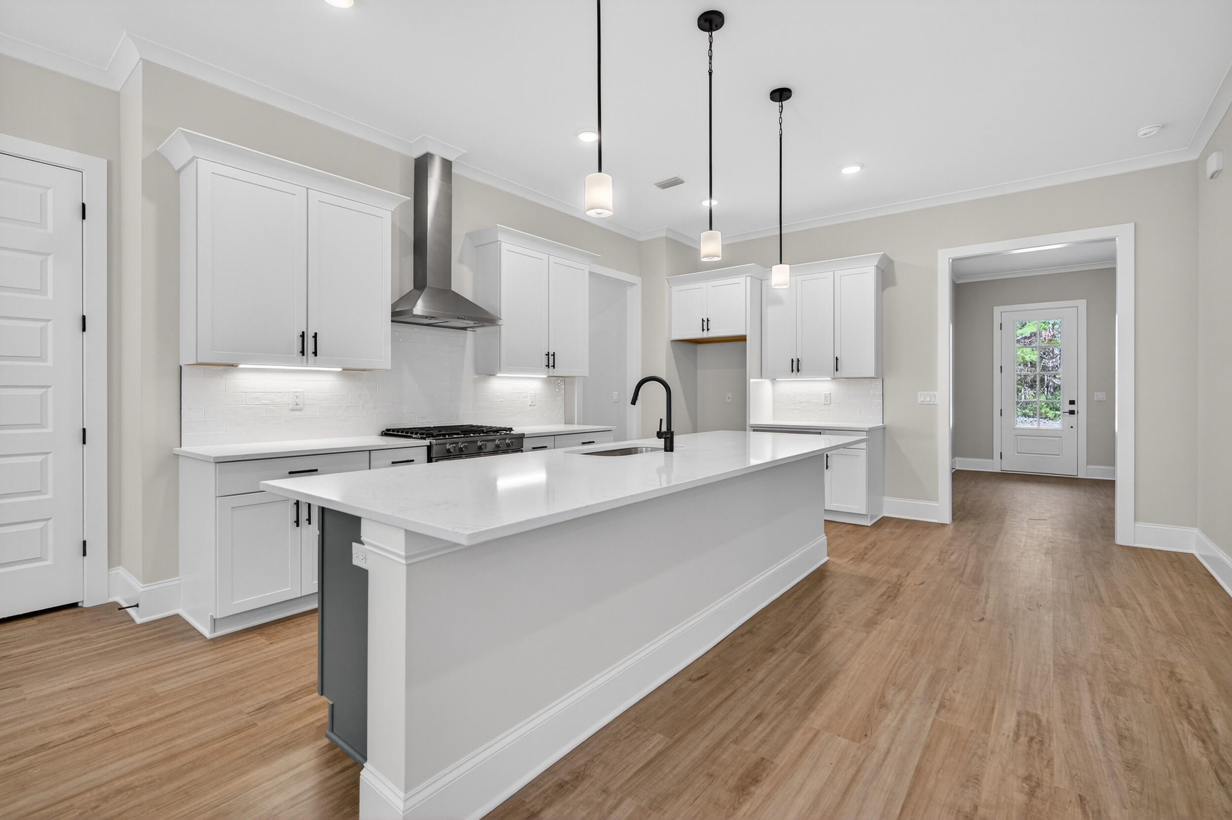 397 North J Hunter's Way, Unit LOT 36 Freeport, FL 32439 - Photo 21 of 54 a large kitchen with stainless steel appliances kitchen island granite countertop a sink a stove a refrigerator and white cabinets with wooden floor