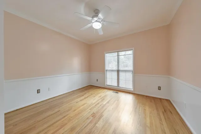 an empty room with chandelier fan and windows