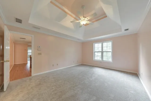 an empty room with chandelier fan and windows