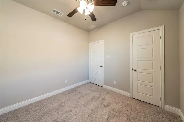 an empty room with a chandelier fan and windows